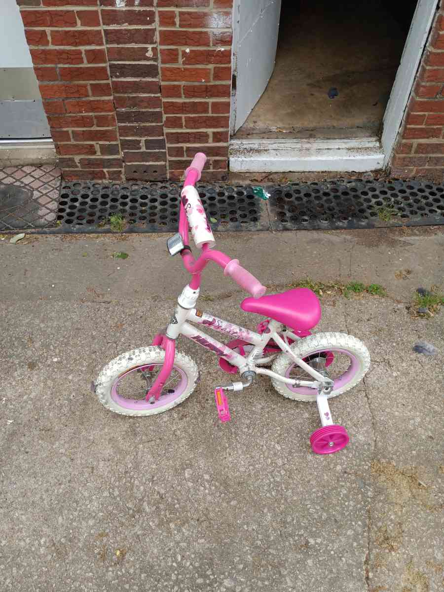 a healthy Barbie pink and white bike with training wheels