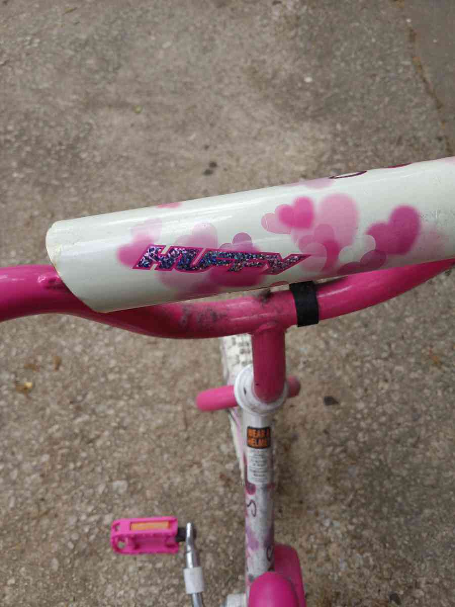 a healthy Barbie pink and white bike with training wheels