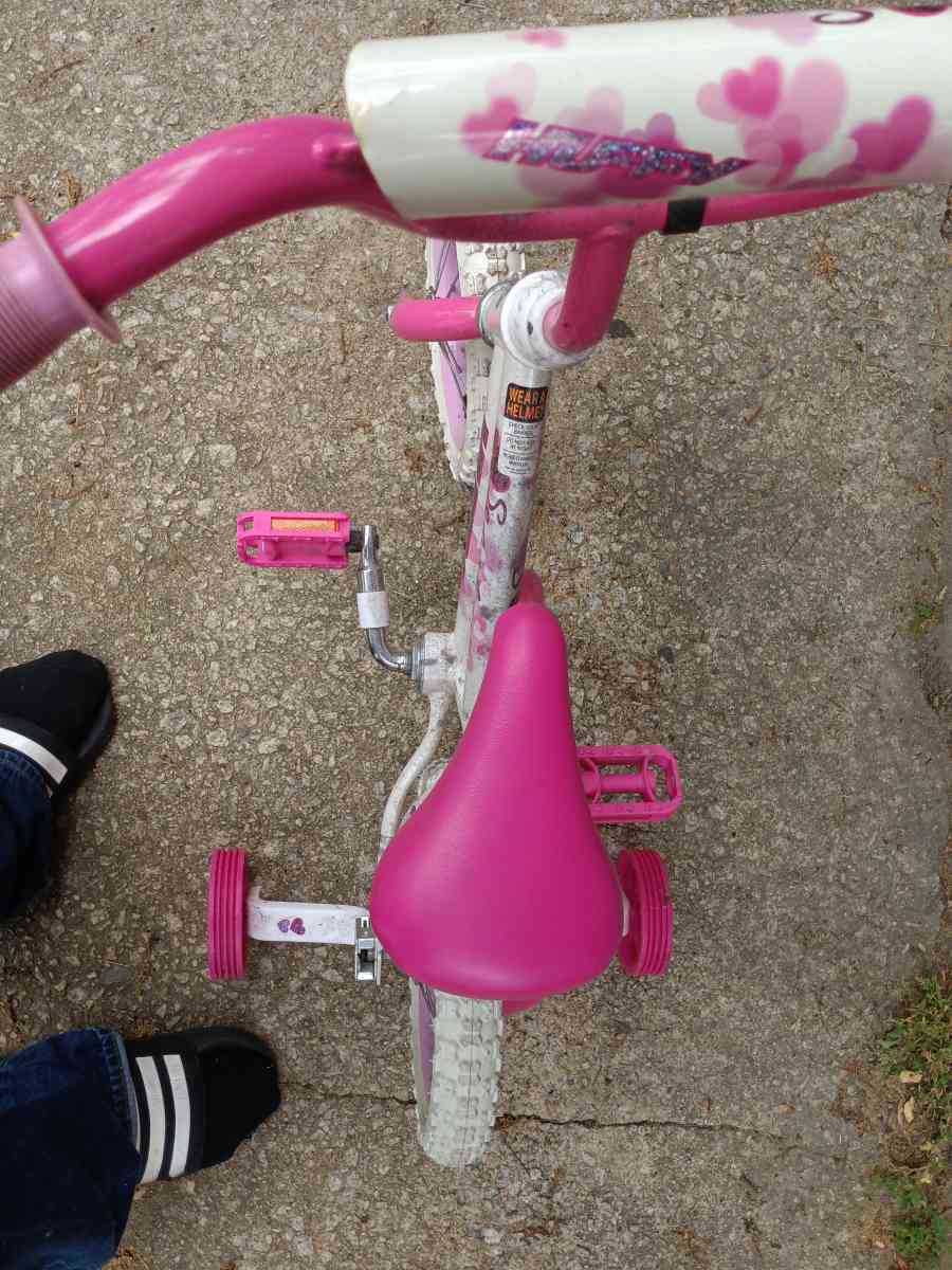 a healthy Barbie pink and white bike with training wheels