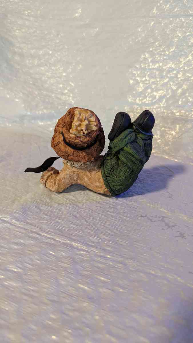 Resin Scarecrow Laying Down With Legs Bent Holding A Crow