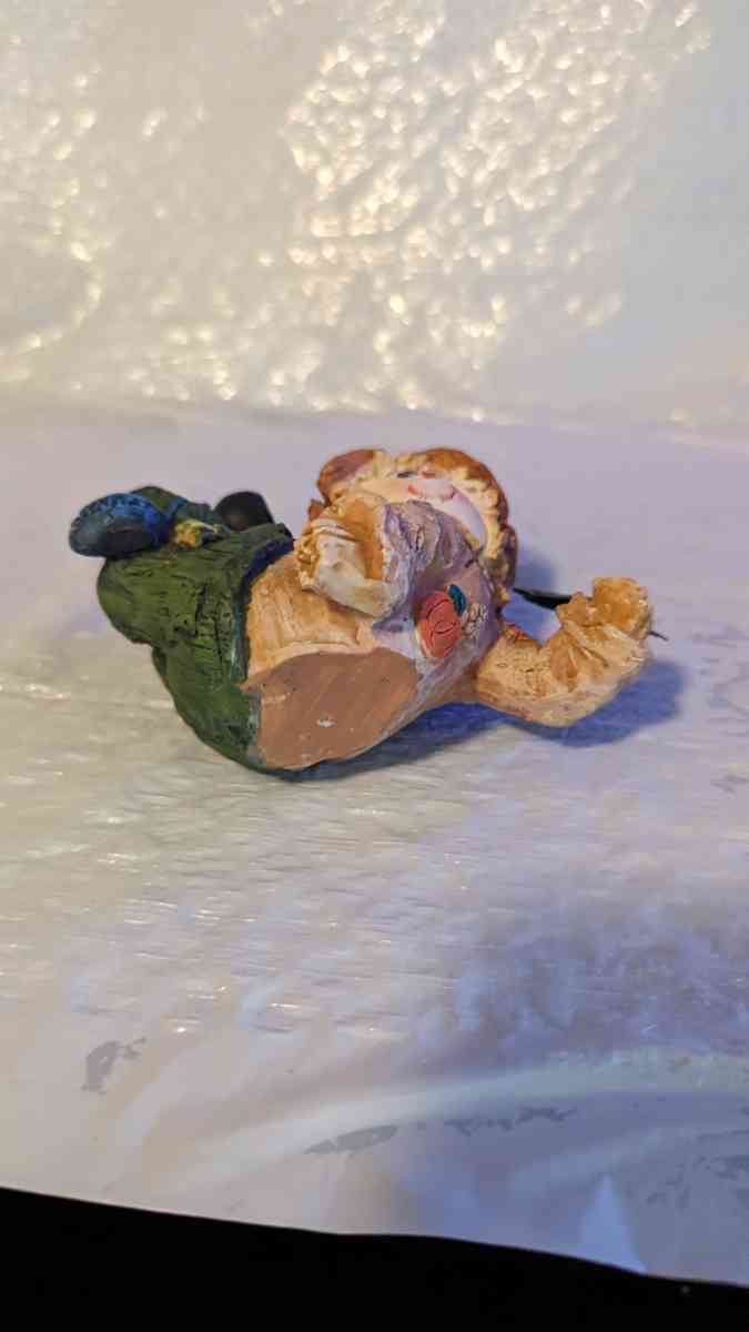 Resin Scarecrow Laying Down With Legs Bent Holding A Crow