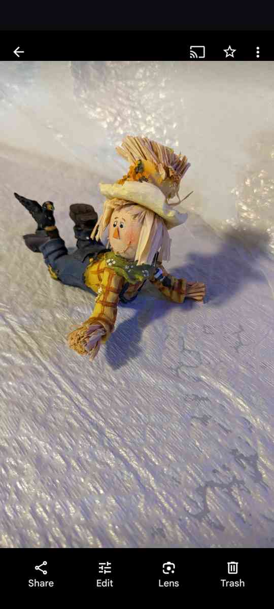 Resin Playful Scarecrow Laying On His Stomach With A Black C